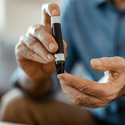 Older man using a finger pricker to test his blood sugar levels.