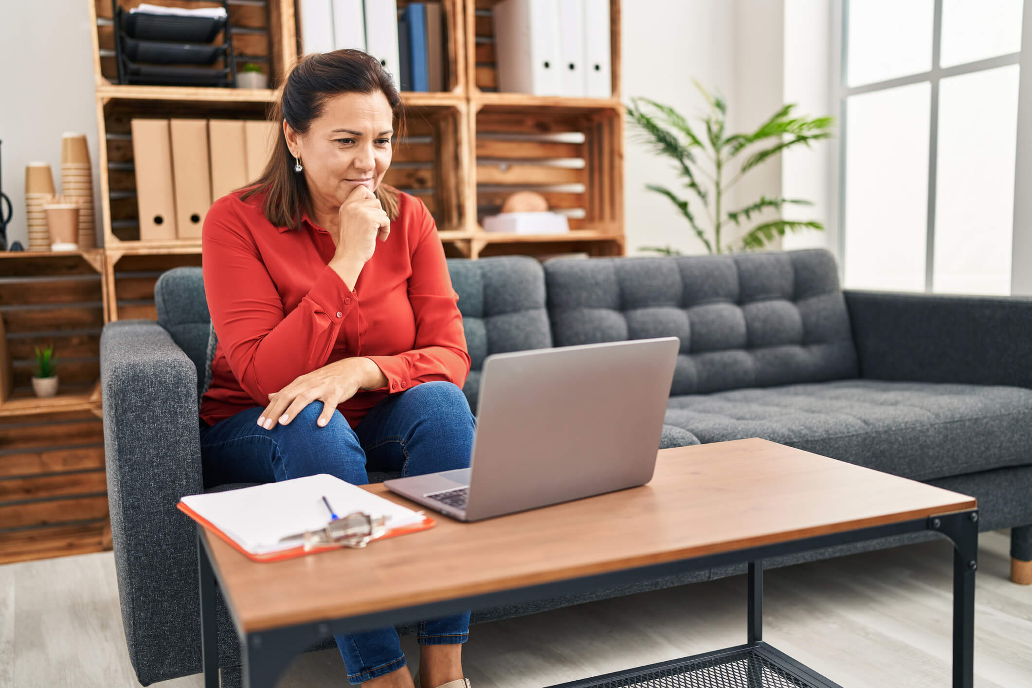 Older woman sitting on a couch talking to the doctor at Advanced Weight Loss Clinic on her laptop.