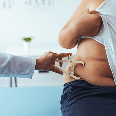 Doctor using prongs to measure the abdominal fat of a patient.