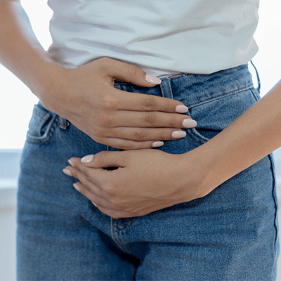 Young woman clenching her lower abdomen in discomfort.