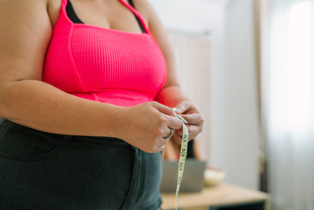 An obese woman measuring her waist after a weight loss diet