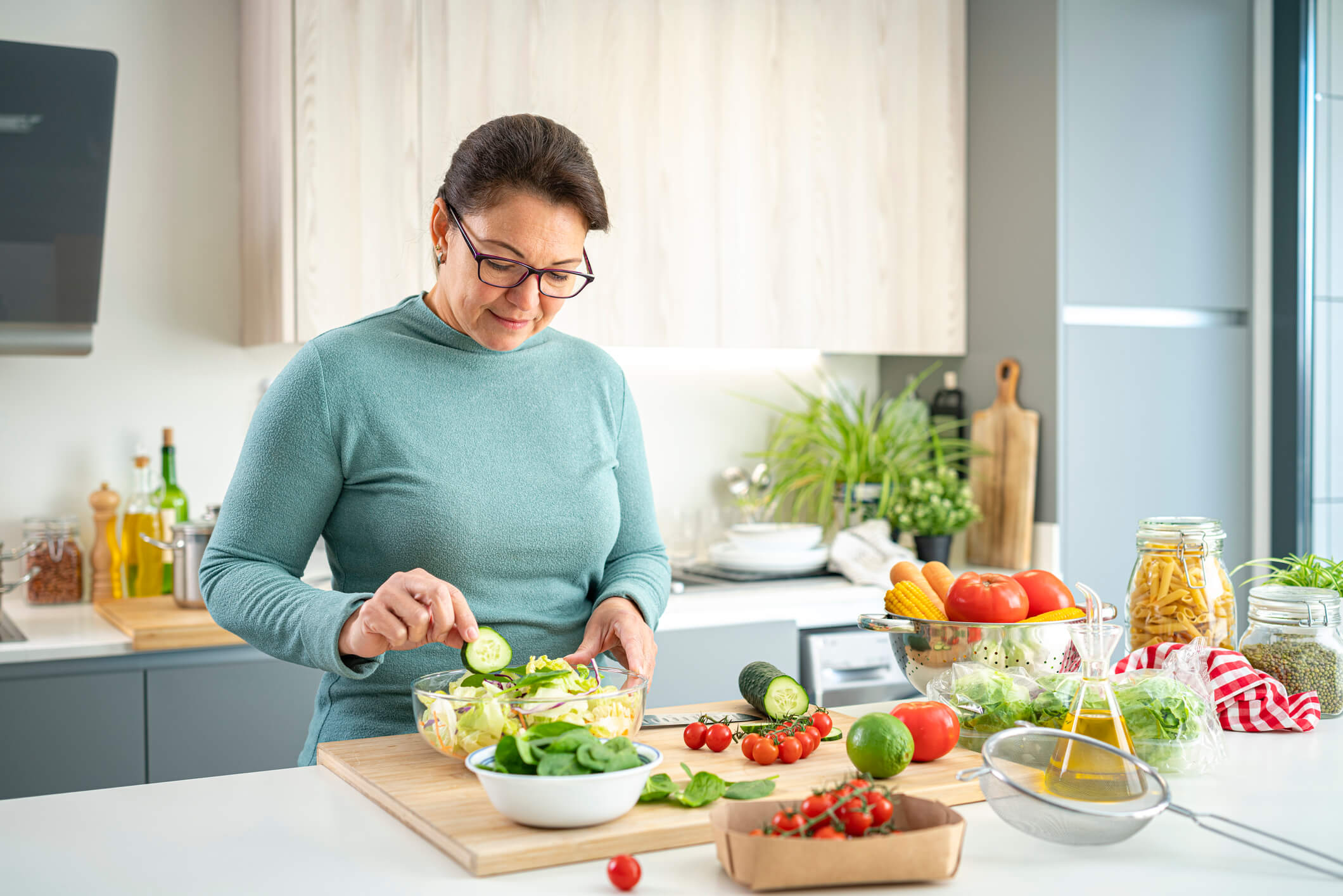 Woman with type 2 diabetes making a healthy salad in her modern kitchen.