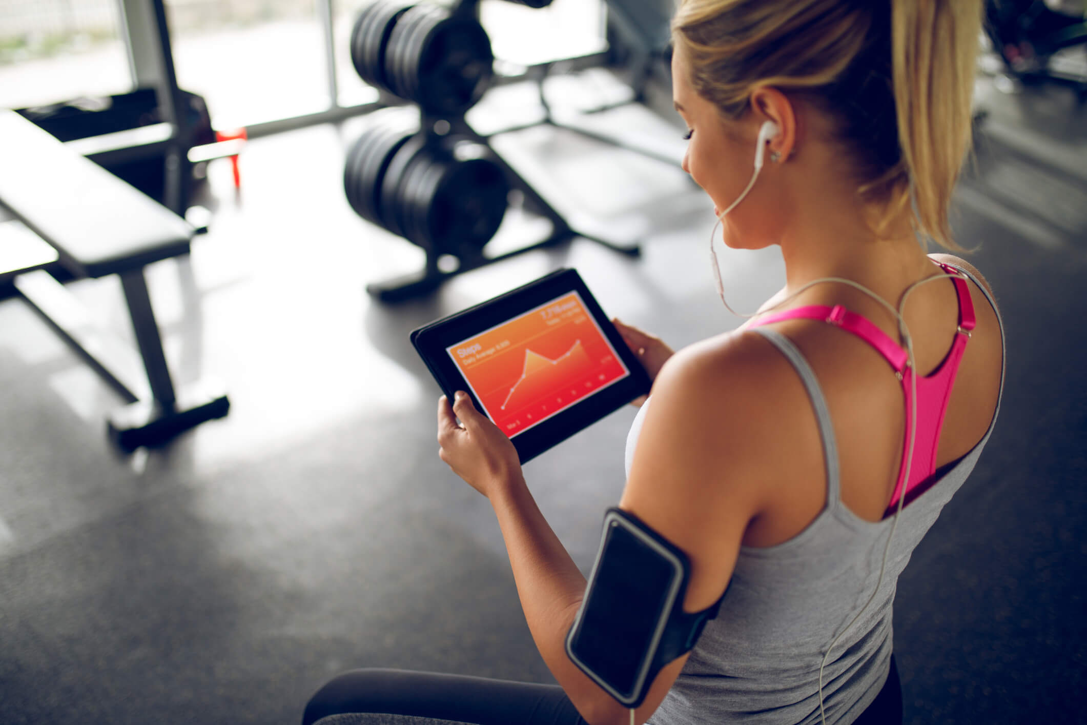 Woman wearing earphones watching her heart rate on a tablet after completing her fitness routine.