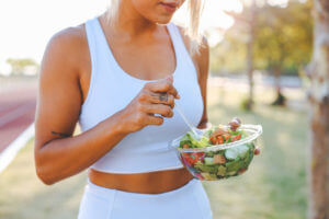 young woman eating a healthy salad after workout. Fitness and healthy lifestyle