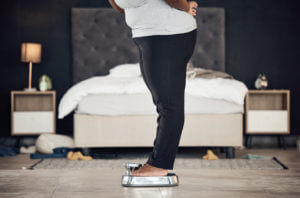 plus size adult weighing to track the results of a weigh loss program